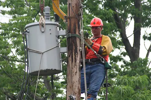 Lineman changing power line clamps on a utility pole